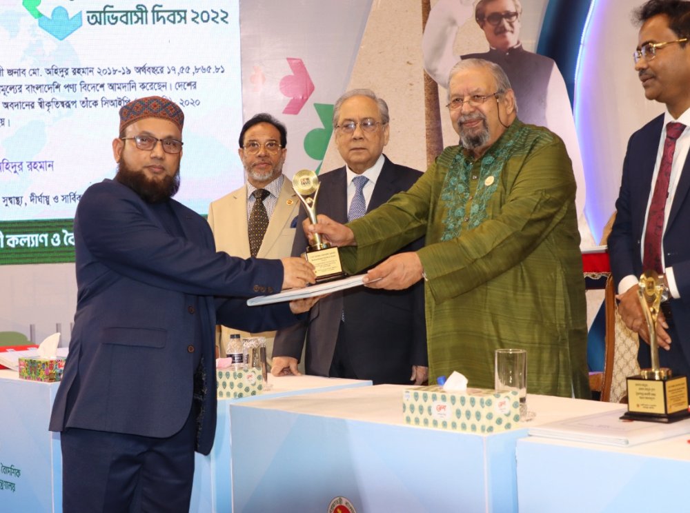 Mohammad Samsul Alam receiving the CIP (NRB) Award trophy on stage at the Probashi Dibas 2022 ceremony